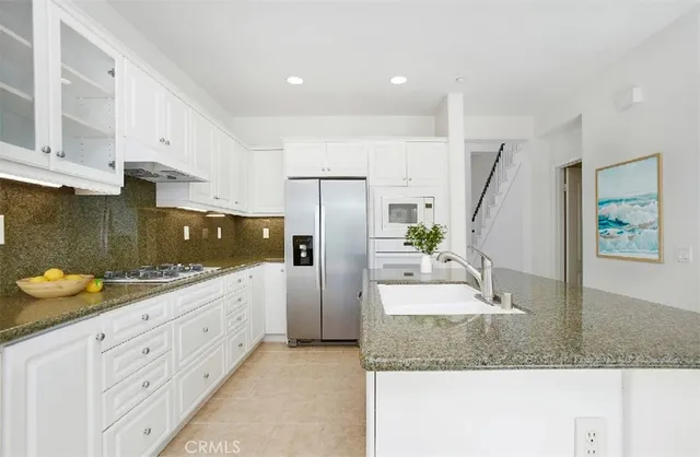 a kitchen with stainless steel appliances granite countertop a sink a stove and a refrigerator