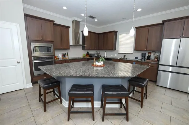 a kitchen with stainless steel appliances granite countertop a table chairs sink refrigerator and microwave