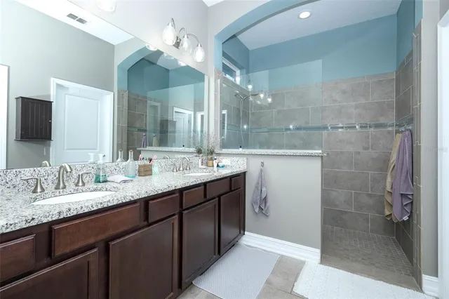 a bathroom with a double vanity sink mirror and shower
