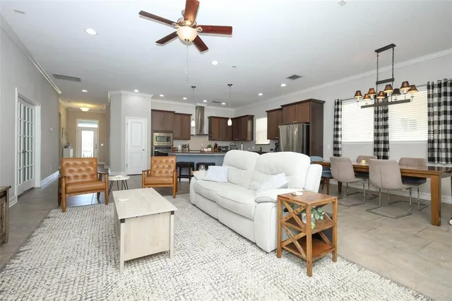 a living room with furniture kitchen view and a chandelier