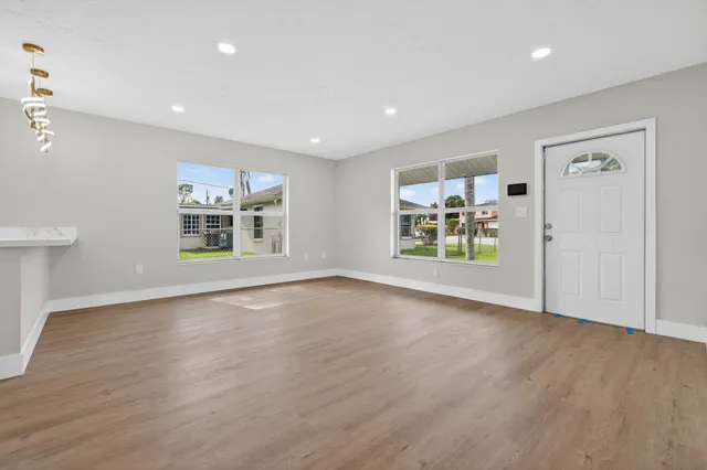 a view of an empty room with a window and wooden floor