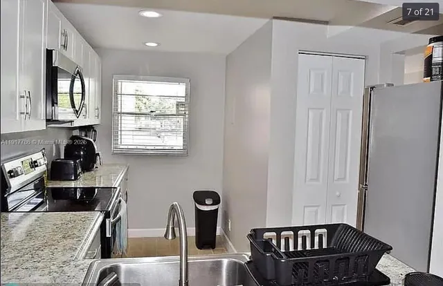 a kitchen with granite countertop a sink a stove and refrigerator