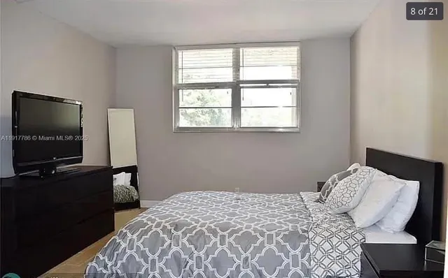 a bedroom with a bed television and a window