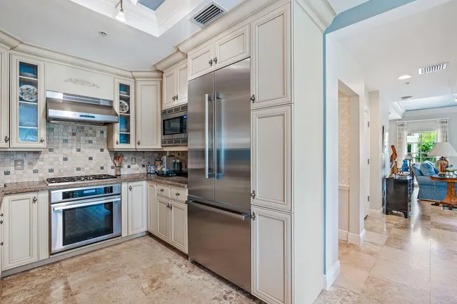 a kitchen with stainless steel appliances granite countertop a refrigerator a stove and a sink