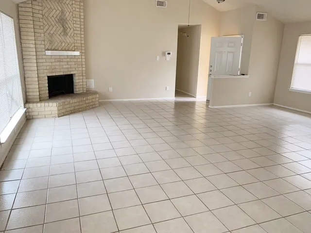 an empty room with windows and fireplace