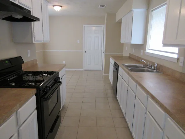 a kitchen with granite countertop a sink stove and cabinets