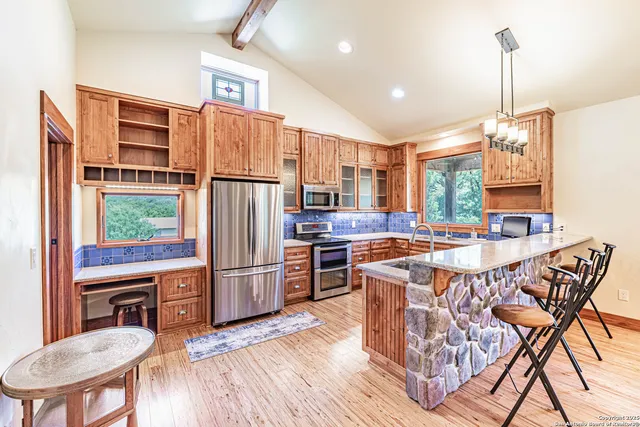 a kitchen with stainless steel appliances granite countertop a refrigerator a stove a sink dishwasher a dining table and chairs with wooden floor