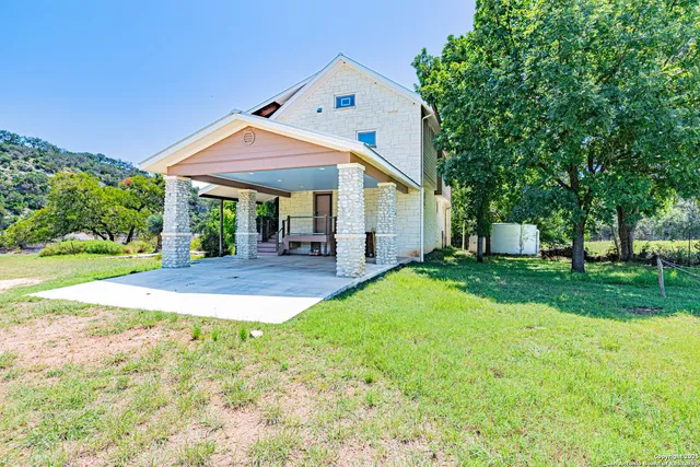 a view of a swimming pool with a yard and large trees