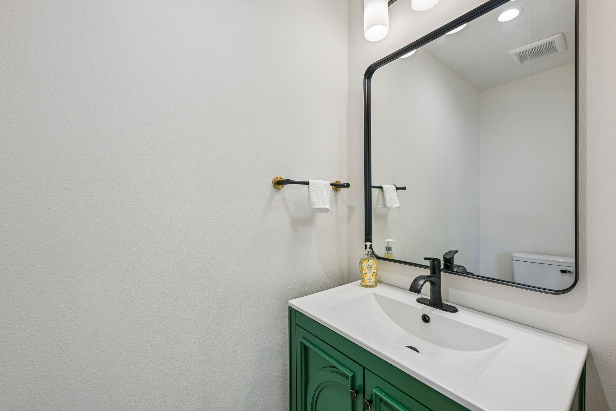 513 West Odell Street, Unit B Austin, TX 78752 - Photo 26 of 38 Modern half bath with vanity with a bold green cabinet and contemporary fixtures.