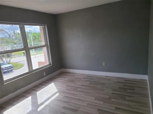 a view of an empty room and wooden floor and windows