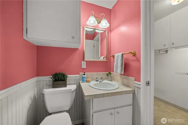 a bathroom with a toilet sink vanity and mirror