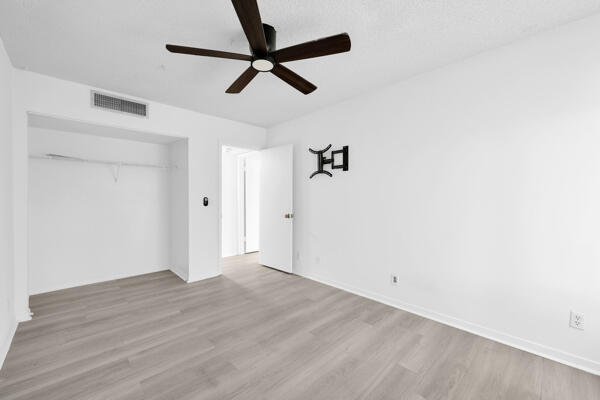150 Pineview Road, Unit J6 Jupiter, FL 33469 - Photo 23 of 27 an empty room with a ceiling fan and wooden floor