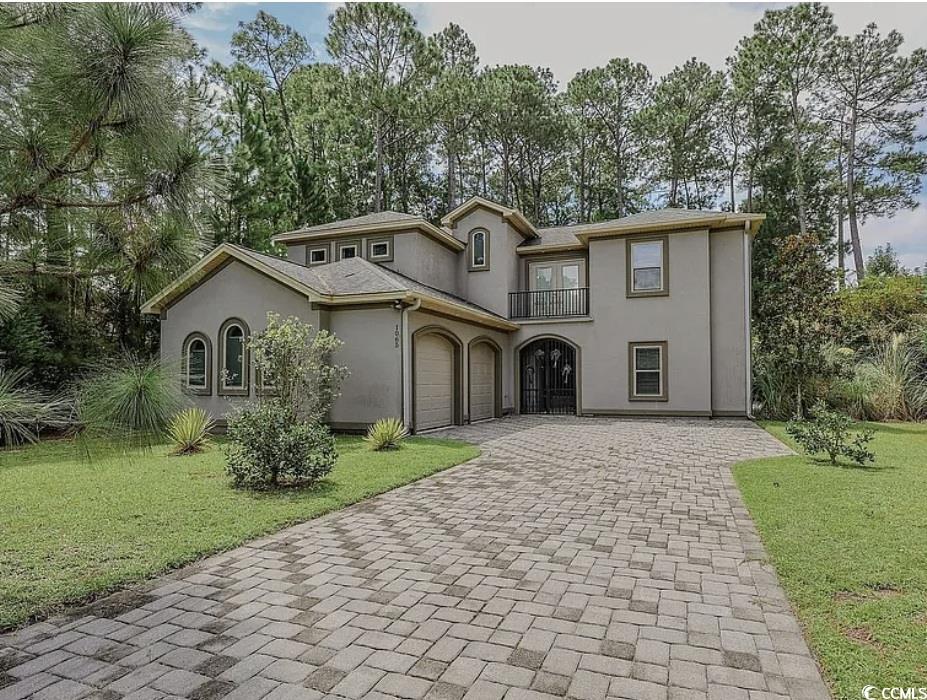Mediterranean / spanish home featuring decorative driveway, a front yard, stucco siding, and a balcony