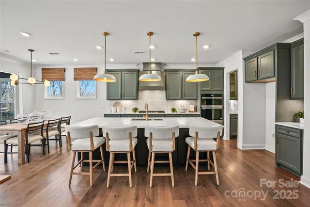 a kitchen with stainless steel appliances kitchen island granite countertop wooden floor dining table and chairs