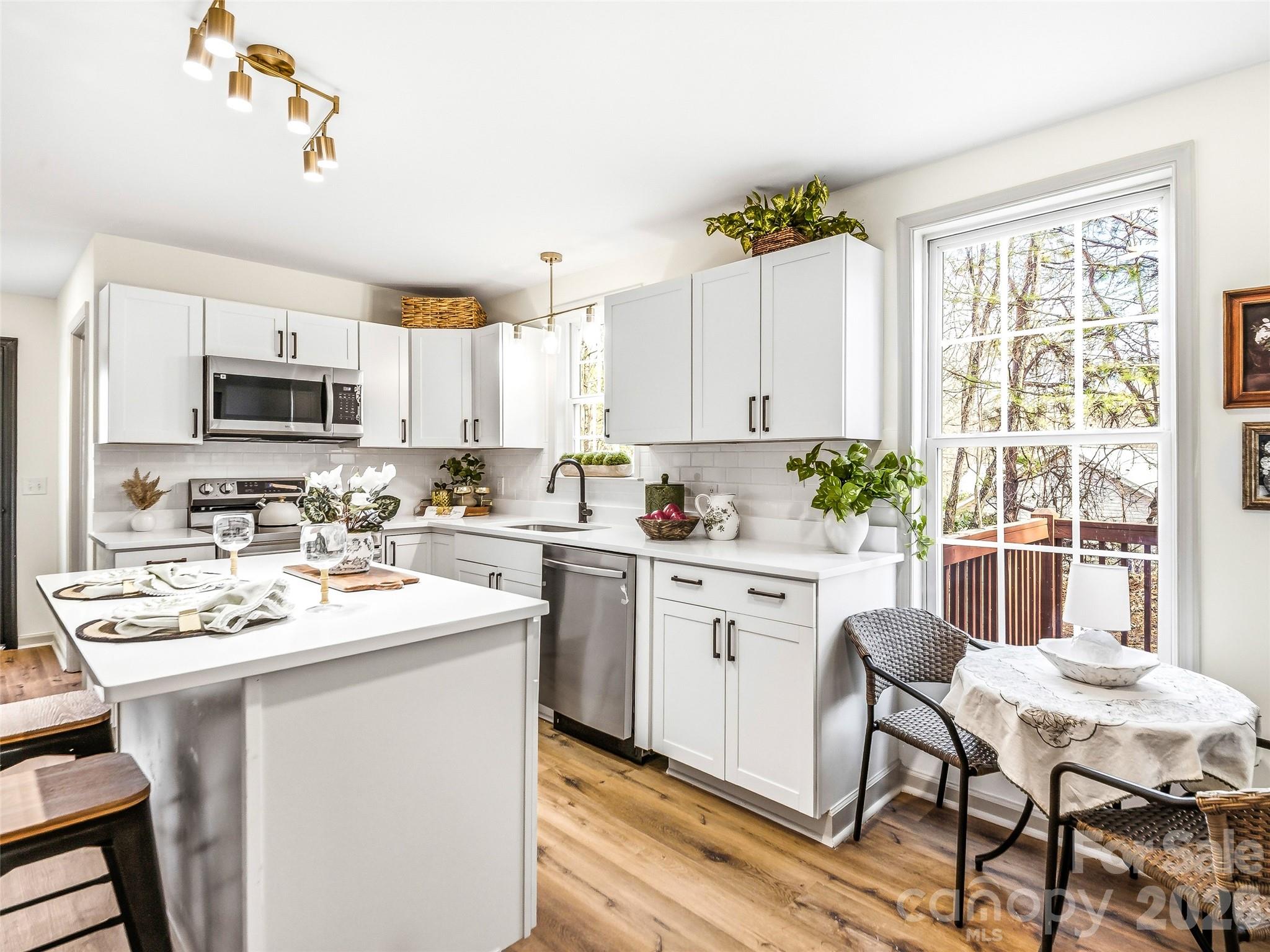 907 Gleason Street Arden, NC 28704 - Photo 14 of 41 a kitchen with a sink stove and white cabinets with wooden floor