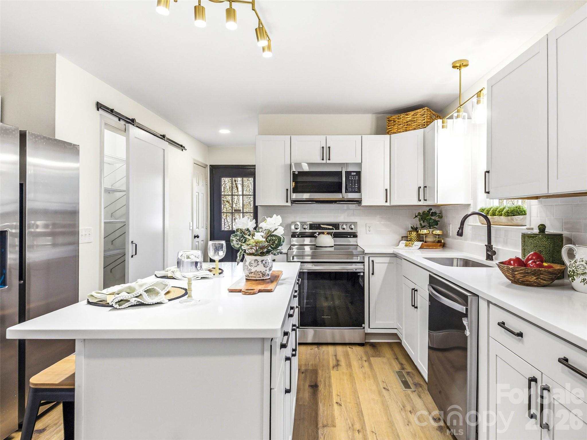 907 Gleason Street Arden, NC 28704 - Photo 20 of 41 a kitchen with a sink a stove top oven a refrigerator cabinets and a dining table