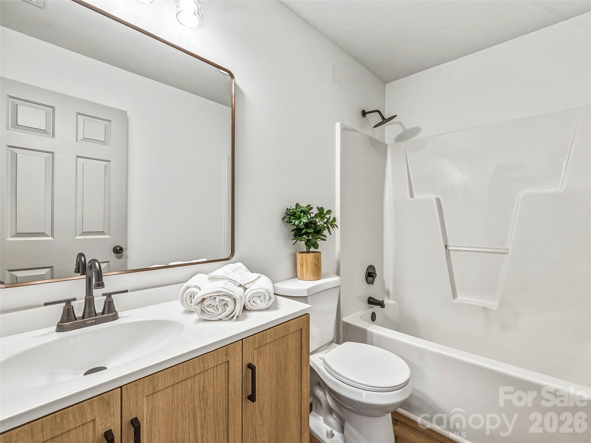 907 Gleason Street Arden, NC 28704 - Photo 30 of 41 a bathroom with a granite countertop sink a toilet a mirror and shower