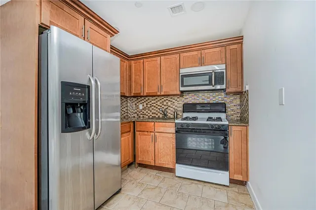 a kitchen with stainless steel appliances granite countertop a refrigerator and a stove top oven