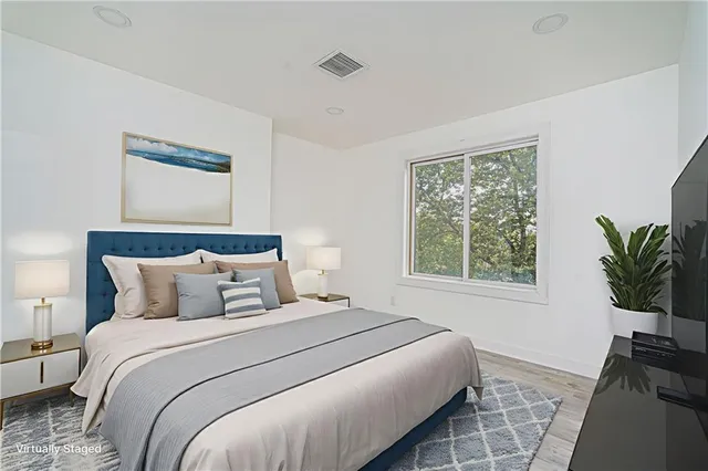 a bedroom with a bed and a potted plant next to a window