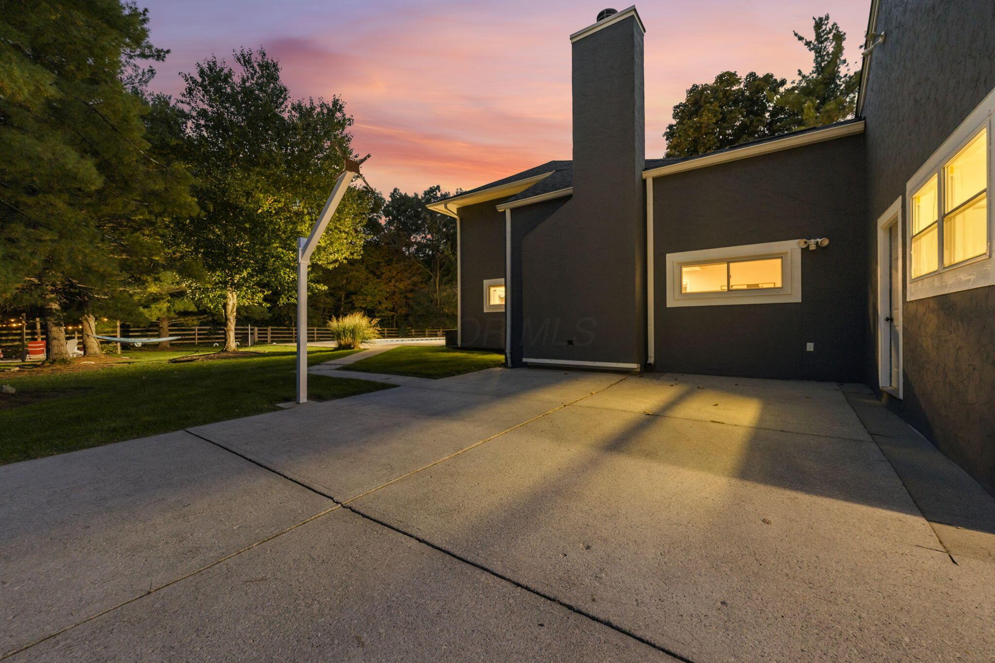 7140 Cook Road Powell, OH 43065 - Photo 22 of 87 Expansive concrete patio with stucco exterior, multiple windows, and a prominent chimney