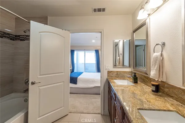 a en suite bathroom with a granite countertop tub sink and mirror