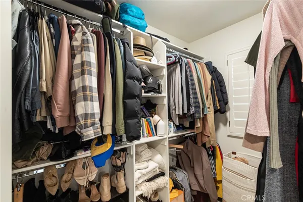 a view of walk in closet with clothes and shoes