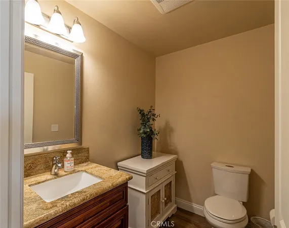 a bathroom with a granite countertop sink vanity mirror and toilet