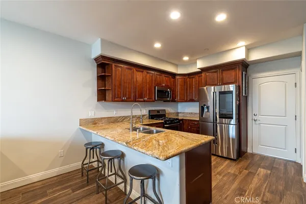 a kitchen with stainless steel appliances granite countertop a refrigerator a sink a stove a microwave and island