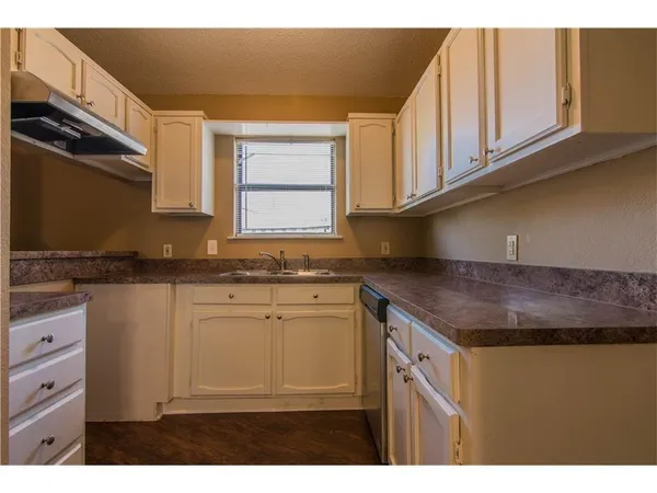 a kitchen with granite countertop a sink cabinets and stainless steel appliances