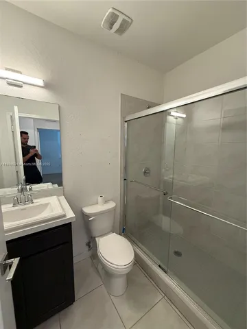 a bathroom with a shower sink vanity mirror and toilet