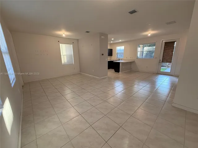 a view of empty room with kitchen and window