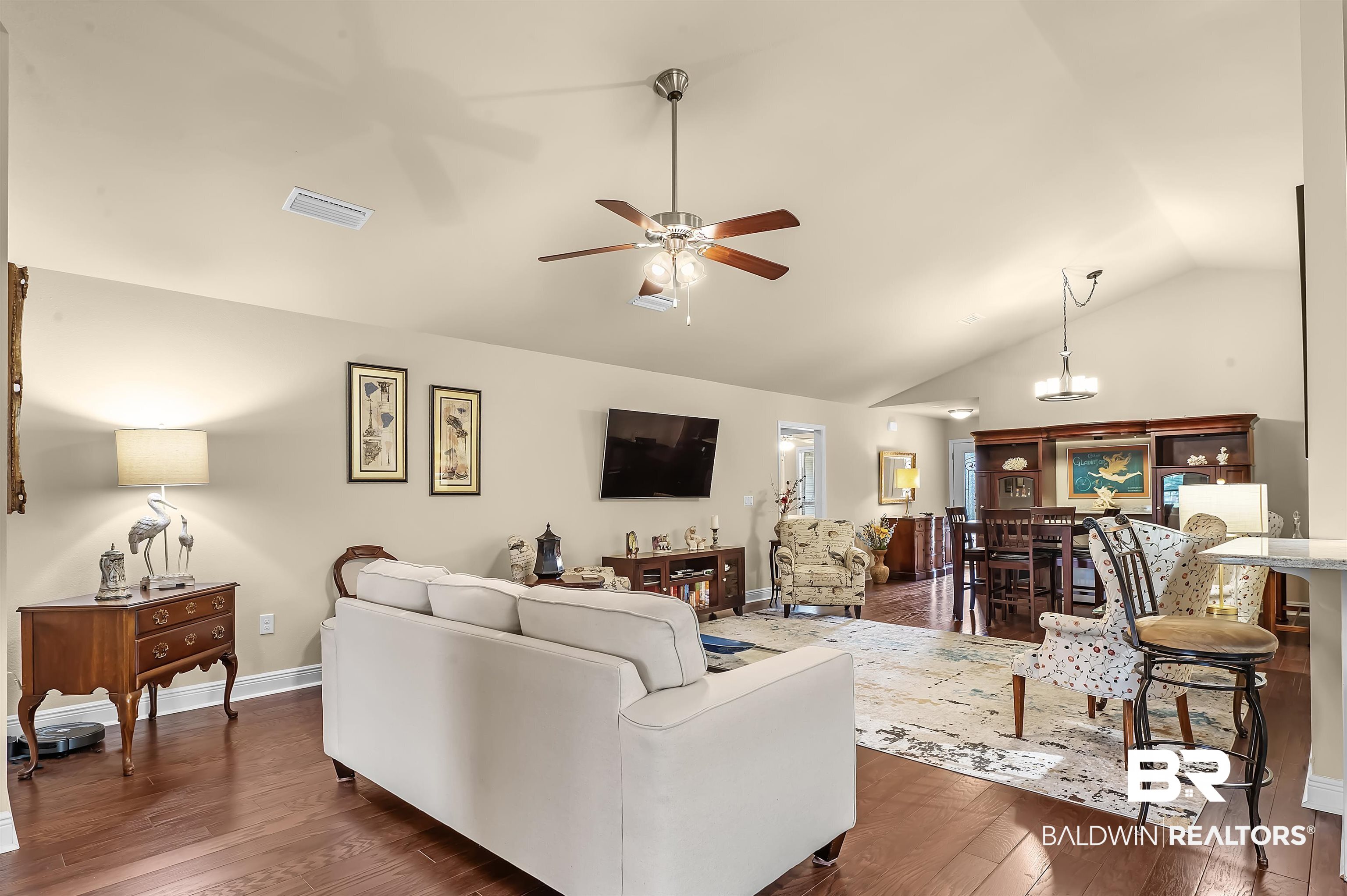 8896 Allay Lane Foley, AL 36535 - Photo 23 of 57 Living room with dark wood-type flooring, vaulted ceiling, and ceiling fan with notable chandelier