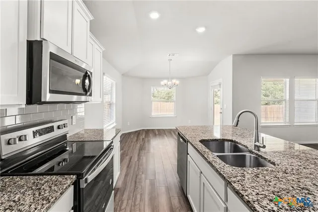 a kitchen with granite countertop a stove a sink a microwave and cabinets