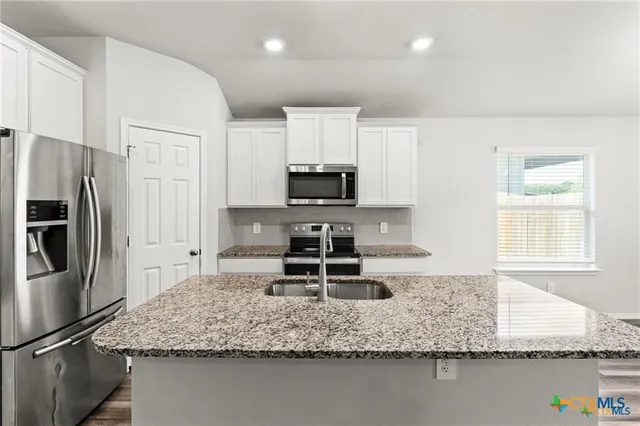 a kitchen with stainless steel appliances granite countertop a sink stove and refrigerator
