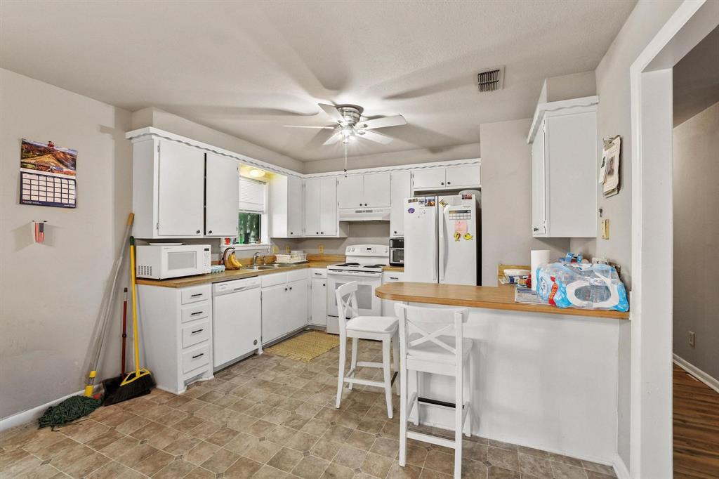 606 Hunter Street Bonham, TX 75418 - Photo 5 of 15 a kitchen with white cabinets and stainless steel appliances