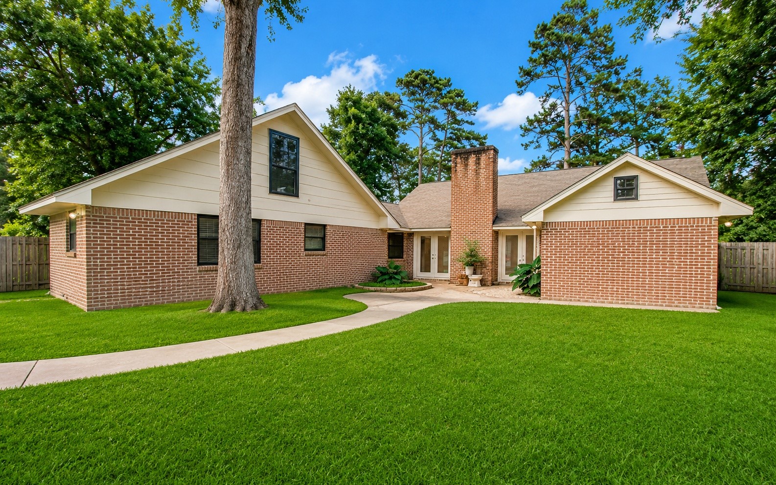 1801 Benbow Way Houston, TX 77080 - Photo 30 of 32 This charming home features a brick exterior with a gabled roof and a central chimney. It is surrounded by lush green lawns and mature trees, offering a serene and inviting atmosphere. The property includes a private walkway leading to the entrance, providing excellent curb appeal.