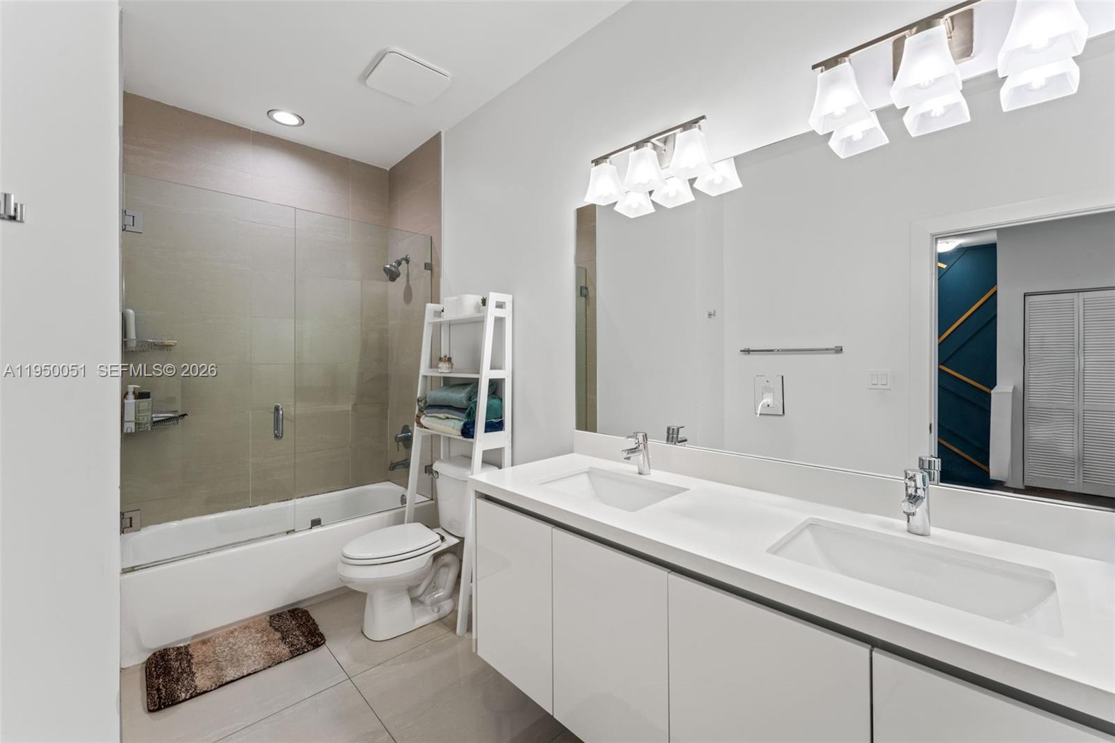 7226 Northwest 103rd Path Doral, FL 33178 - Photo 27 of 38 a bathroom with a double vanity sink toilet mirror and shower