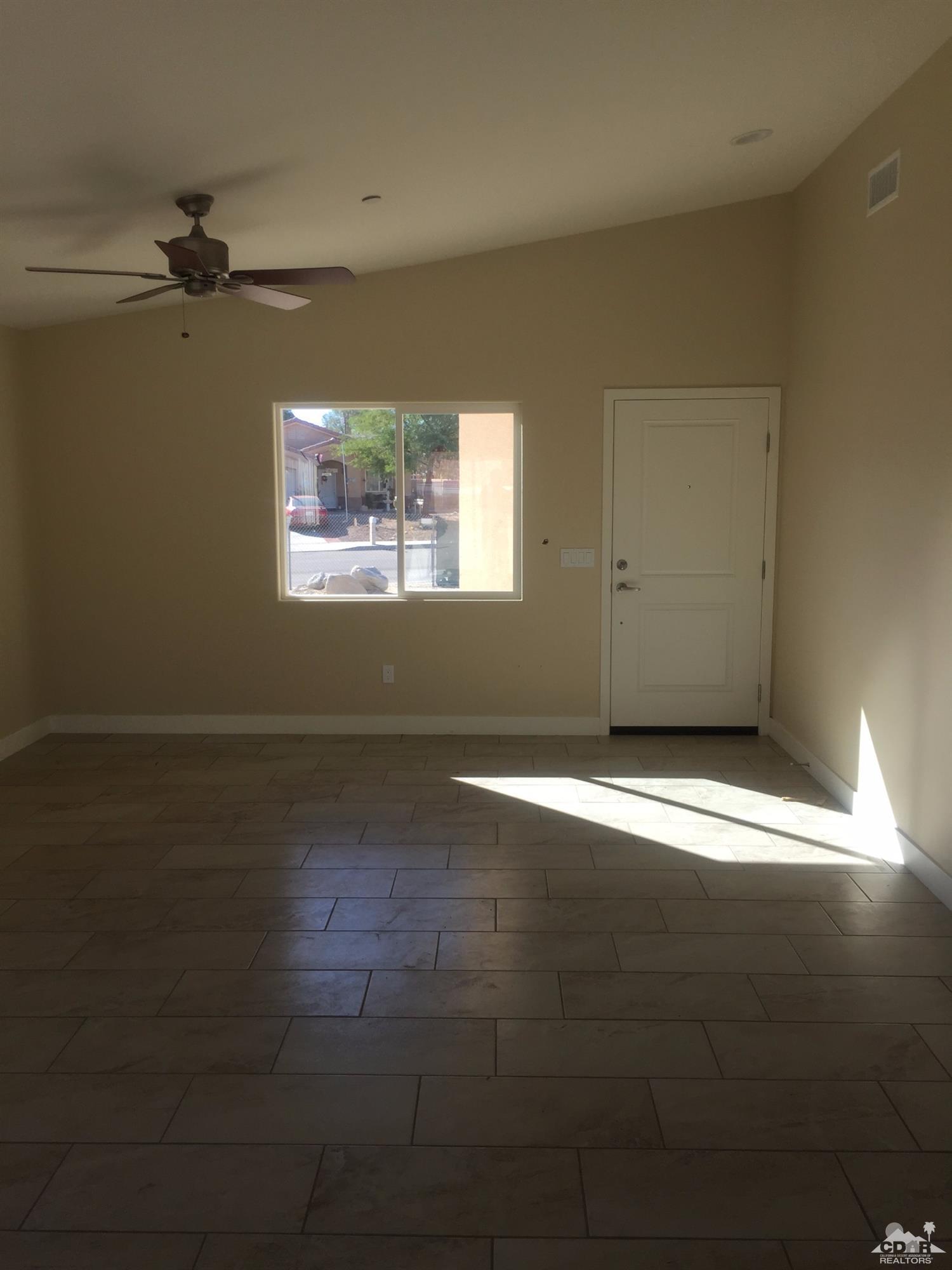 13689 Ocotillo Road Desert Hot Springs, CA 92240 - Photo 6 of 9 an empty room with wooden floor and windows