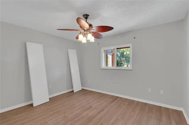 an empty room with wooden floor chandelier fan and closet