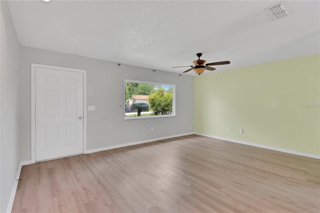 6366 Southwest 115th Street Road Ocala, FL 34476 - Photo 5 of 45 a view of a room with wooden floor and a ceiling fan