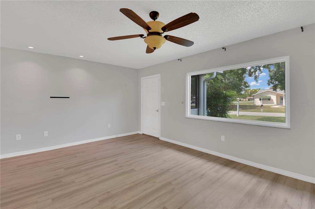 6366 Southwest 115th Street Road Ocala, FL 34476 - Photo 6 of 45 a view of an empty room with wooden floor and ceiling fan