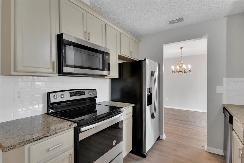 6366 Southwest 115th Street Road Ocala, FL 34476 - Photo 9 of 45 a kitchen with granite countertop wooden cabinets and stainless steel appliances