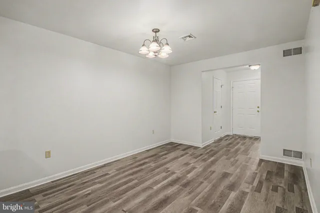 a view of an empty room with window and chandelier fan