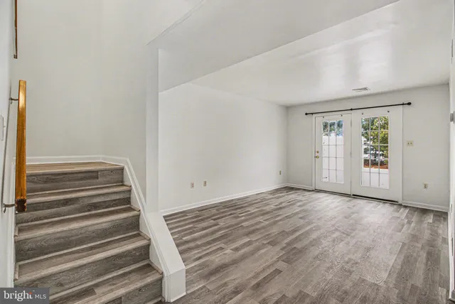 a view of an empty room with wooden floor and windows