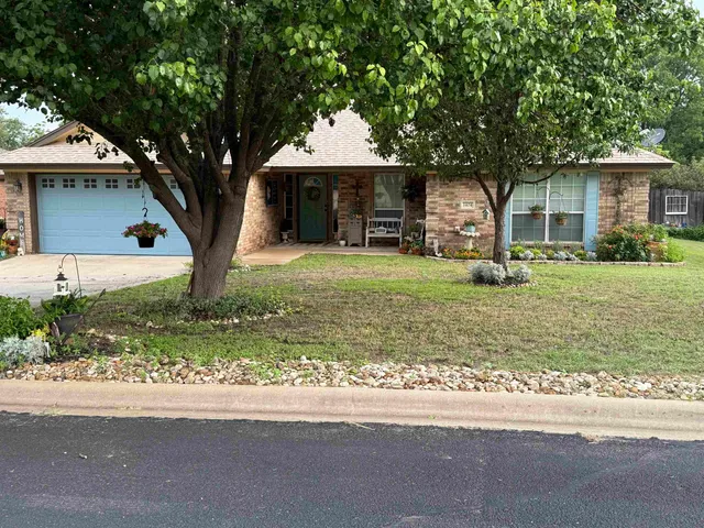 a front view of a house with a garden and trees