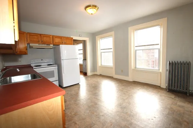 a kitchen with a refrigerator a stove top oven a sink and a window