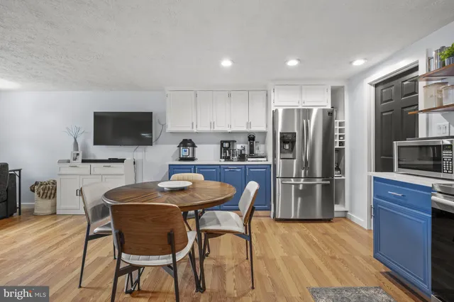 a kitchen with stainless steel appliances a refrigerator a stove a sink dishwasher a dining table and chairs with wooden floor