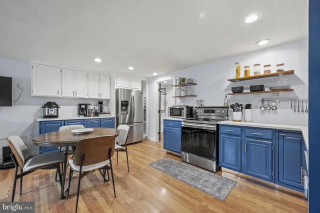 a kitchen with stainless steel appliances granite countertop a stove top oven a sink dishwasher and a refrigerator with wooden cabinets