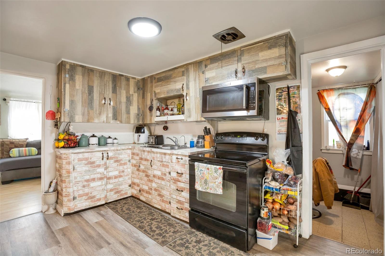 6830 Olive Street Commerce City, CO 80022 - Photo 6 of 25 a kitchen with stainless steel appliances a stove microwave and sink