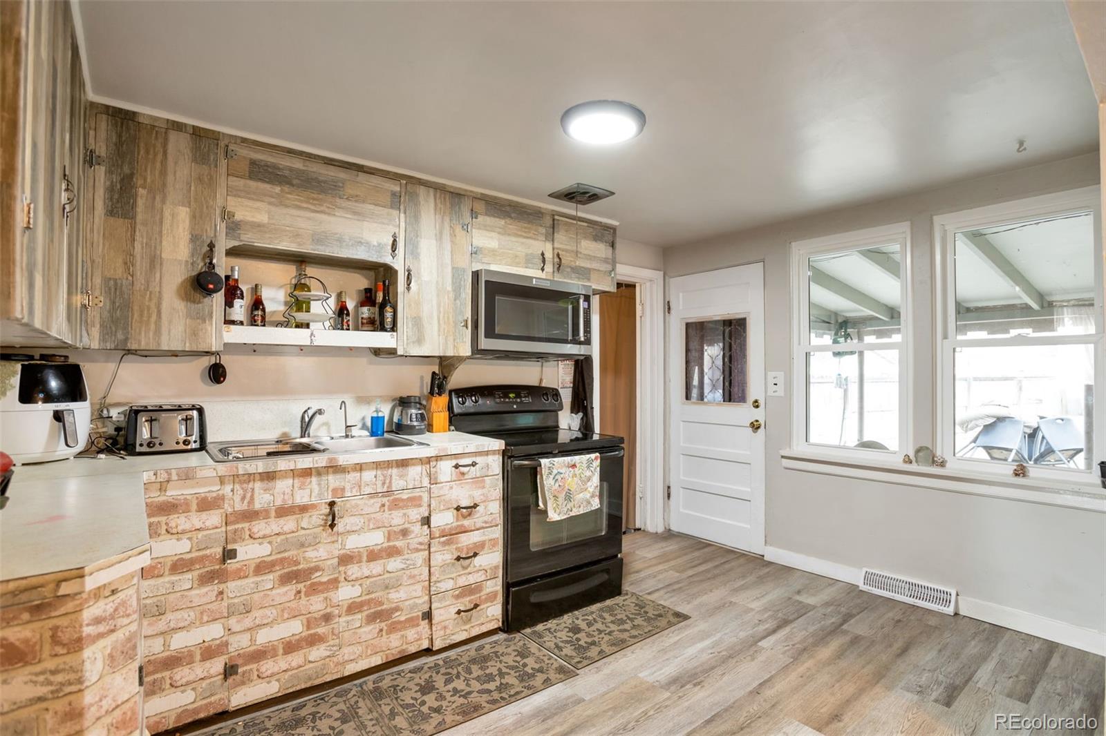 6830 Olive Street Commerce City, CO 80022 - Photo 8 of 25 a kitchen with granite countertop a stove a sink and a refrigerator